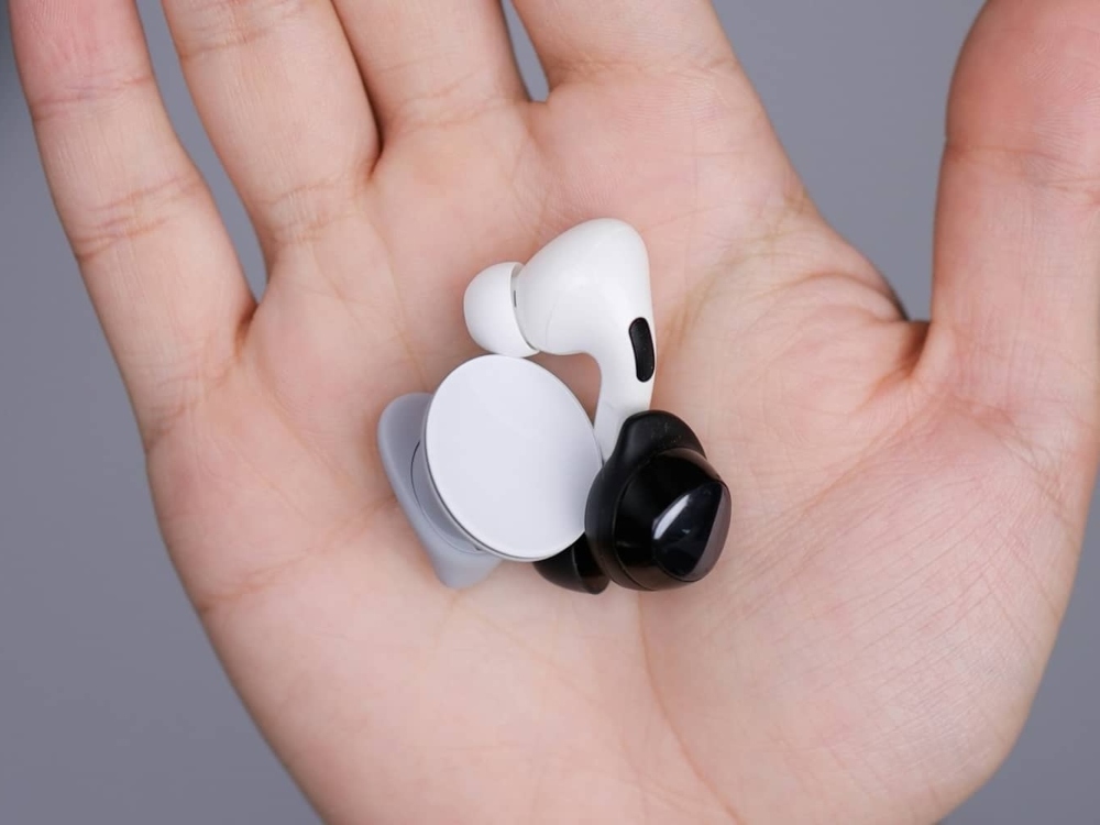 Earbud-style over-the-counter hearing aids held in an open palm, compared with fitted devices in Falconer, NY